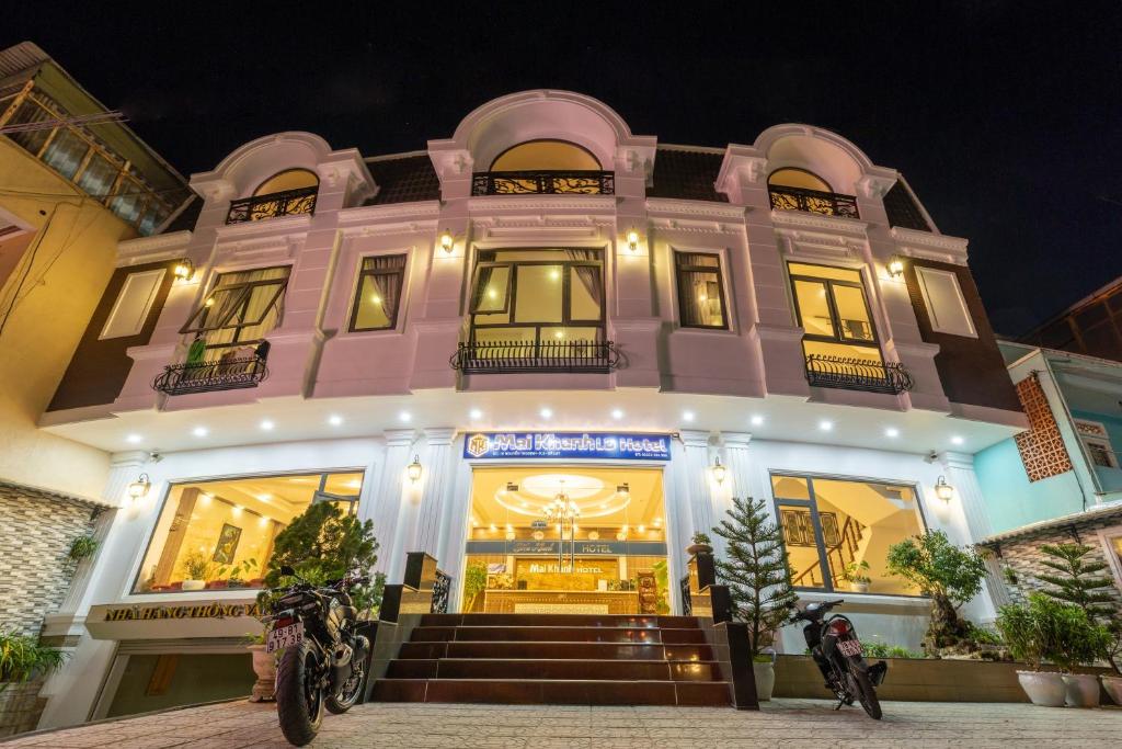 ein rosafarbenes Gebäude mit Motorrädern, die davor geparkt sind in der Unterkunft Mai Khanh Hotel in Da Lat