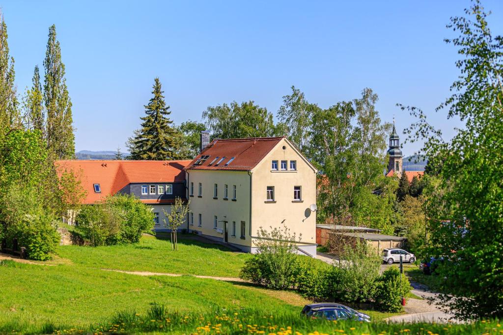 ein Haus auf einem Feld mit einer Kirche im Hintergrund in der Unterkunft Ferienwohnung Sprejnik - Residenz Sonnenhübel in Großschönau