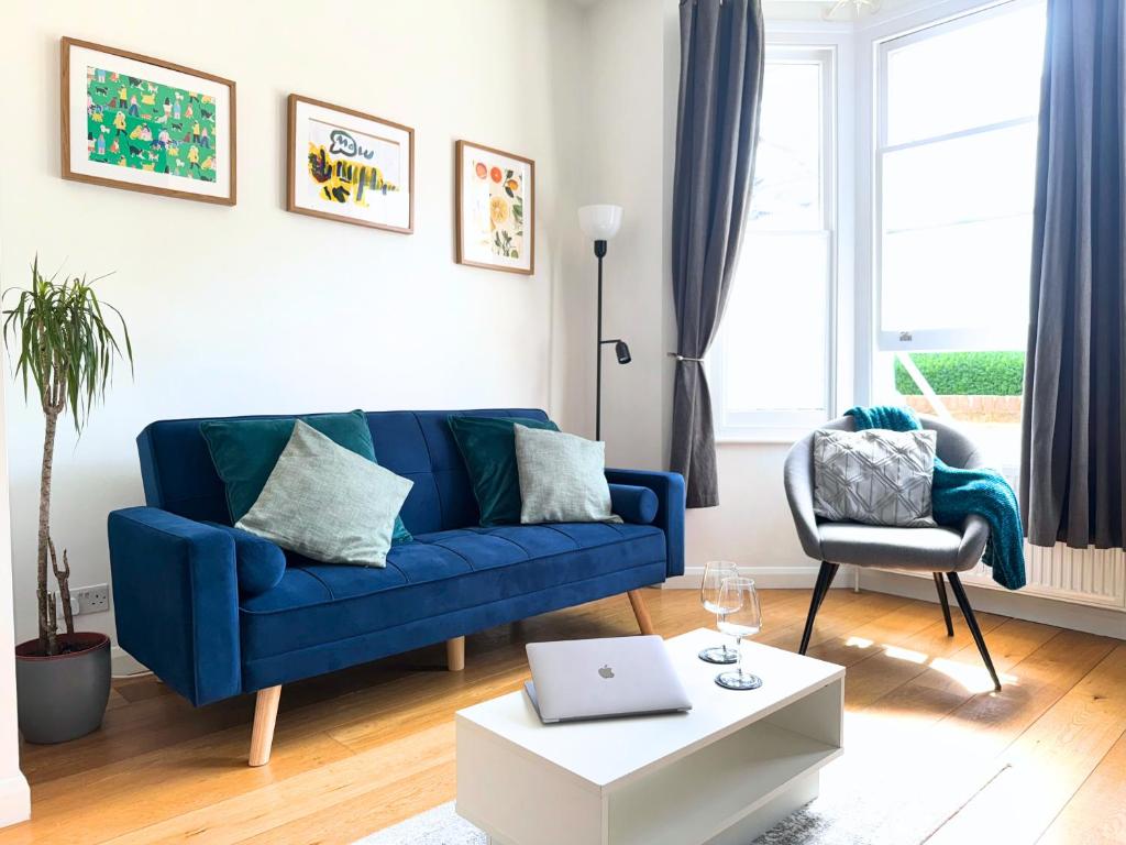 a living room with a blue couch and a chair at Broomsleigh NW6 Apartment in London