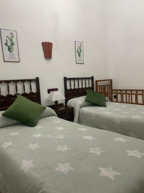 a bedroom with two beds with green and white blankets at La magnolia in La Puerta de Segura