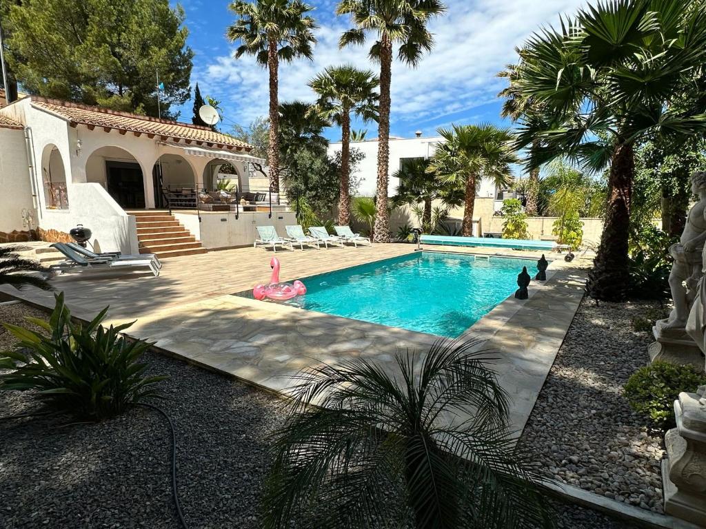een zwembad met palmbomen en een huis bij Casa El Mirador in Calpe