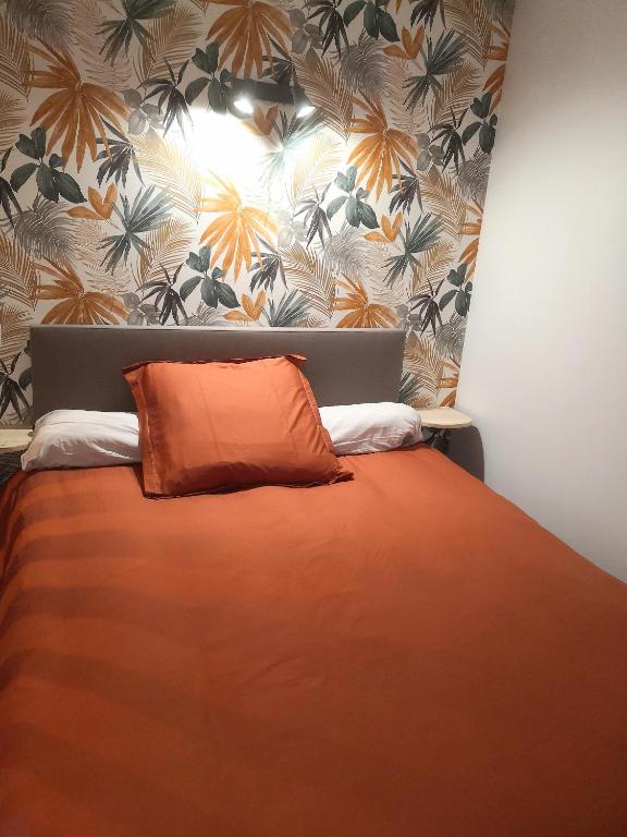 une chambre avec un lit orange avec un papier peint fleuri dans l'établissement Appartement des Charmilles, Compiègne hyper-centre, à Compiègne