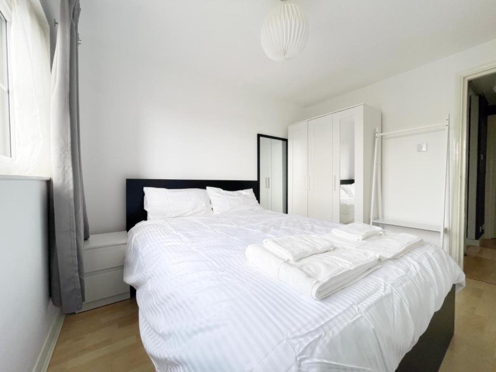 a white bed with white sheets and pillows on it at Colliers Wood 1 Bed South London Short Stay in Mitcham