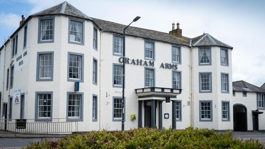 Graham Arms Inn في Longtown: مبنى ابيض وكلمة فن غاني