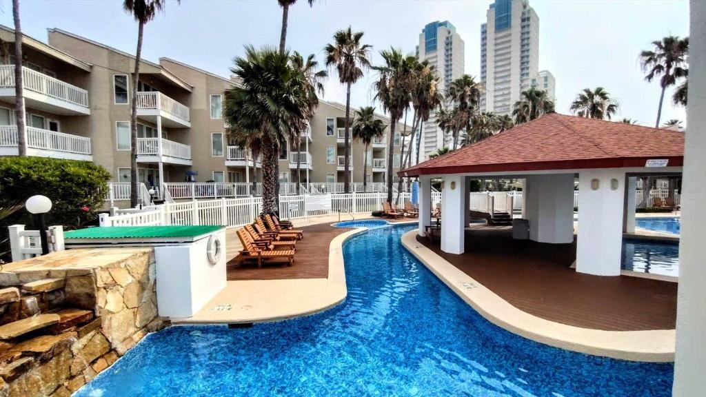 una piscina en un complejo con palmeras y edificios en GULFPOINT 1303 condo en South Padre Island