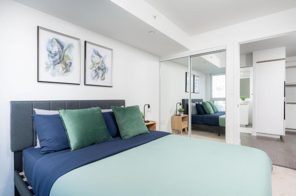 1 dormitorio con 1 cama con almohadas azules y verdes en 2 Beds - Sleeps 3 beside U of T!, en Toronto