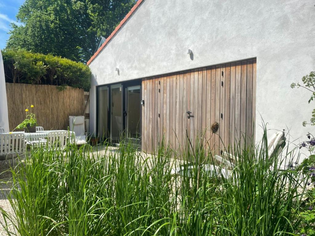 een huis met houten deuren en hoog gras bij Huisje Hendrik in Baarn