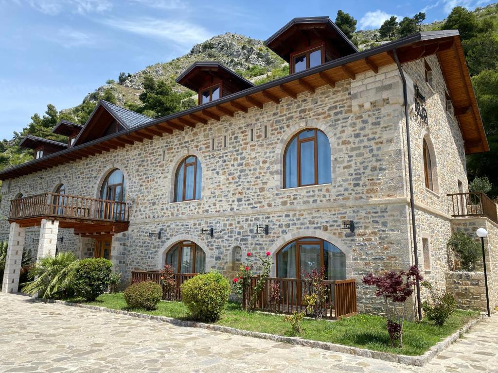 a stone house with a mountain in the background at Hotel Guri Shengjin in Lezhë