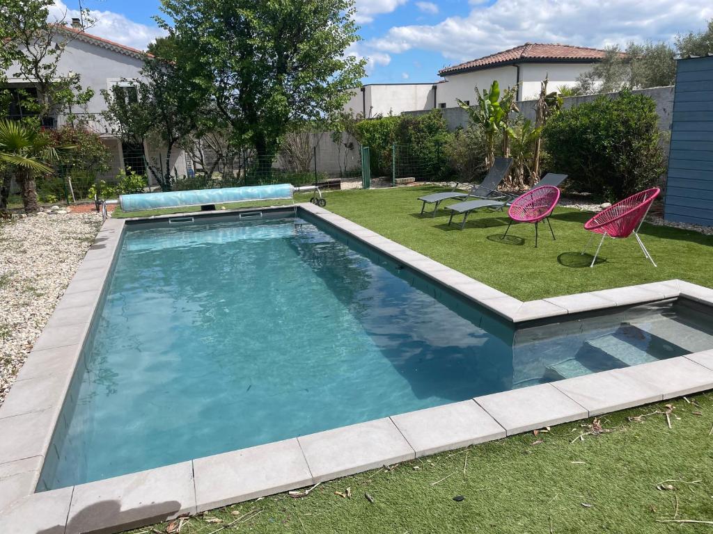 - une piscine dans une cour avec 2 chaises roses dans l'établissement Appartement rez de chaussée maison indépendant avec piscine, à Saint-Christol-lès-Alès