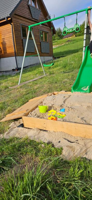 a sandbox with a swing and a toy in the sand at Nad Cicha in Ujsoły