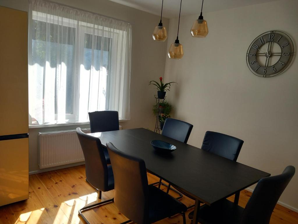 a dining room table with chairs and a clock on the wall at Territory Parking RV&Campers Garden Forest park in Rīga