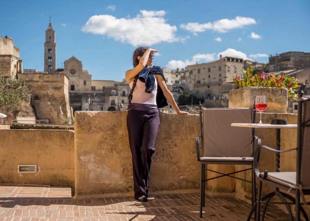 a woman standing on a wall talking on a cell phone at Locanda Di San Martino Hotel & Thermae Romanae in Matera