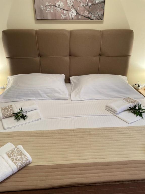 a bed with white pillows and towels on it at Denis Apartment in Ždrelac