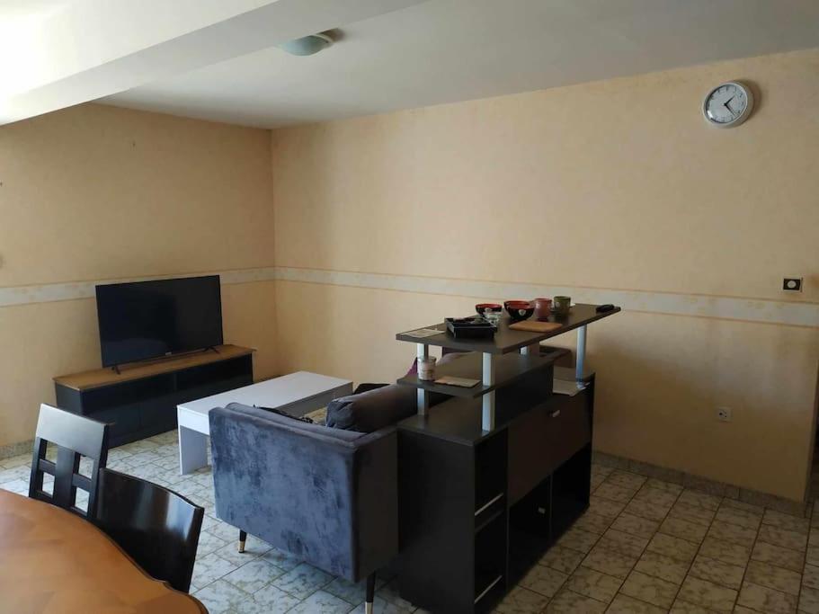 a room with a couch and a clock on the wall at Jolie longère au calme proche du Futuroscope in Saint-Georges-lès-Baillargeaux