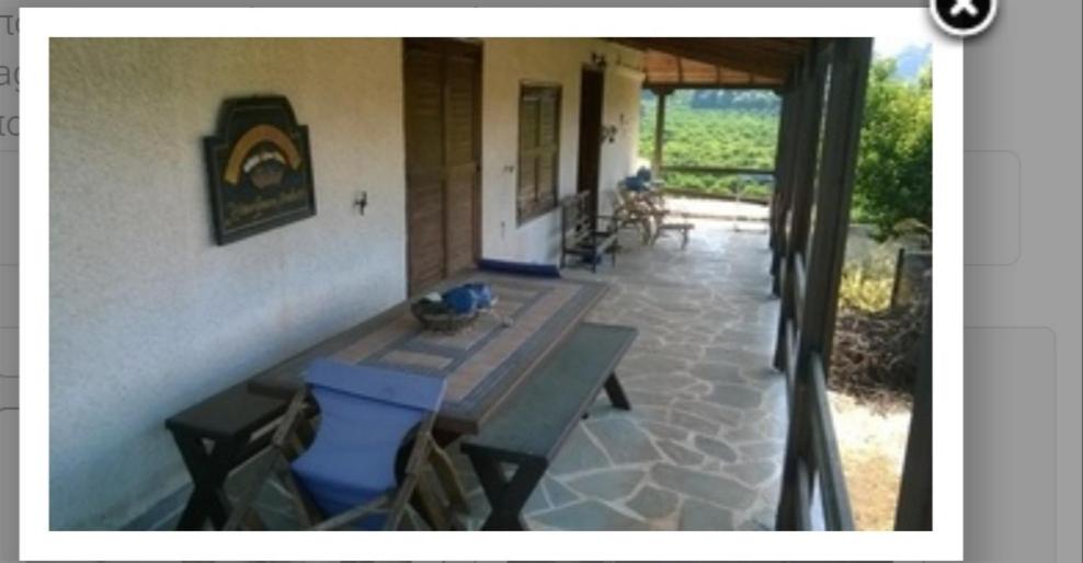 a porch of a house with a table and a fireplace at Fanis in Paralía Néas Epidhávrou