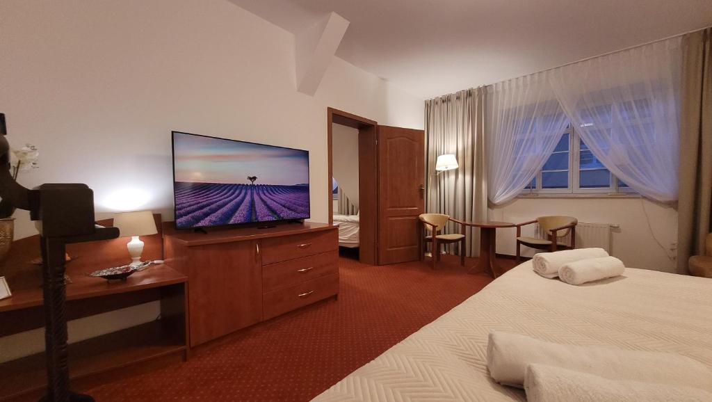 a hotel room with a flat screen tv on a dresser at Hotel Maxim Kwidzyn in Kwidzyn