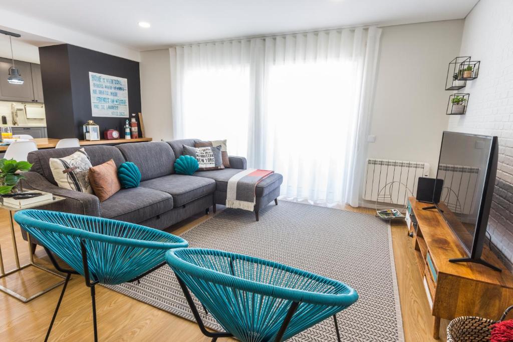 a living room with a couch and two blue chairs at Just Like Home - Moledo Waves in Moledo