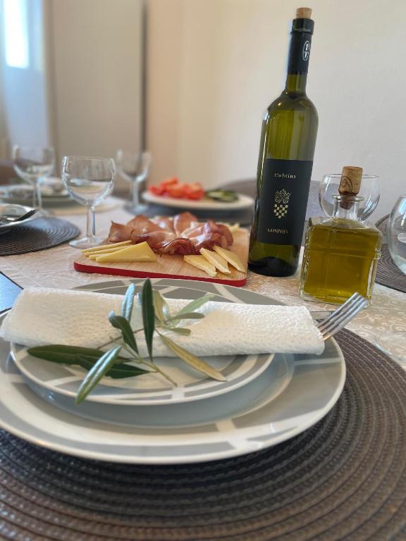 a table with a plate of food and a bottle of wine at Denis Apartment in Ždrelac