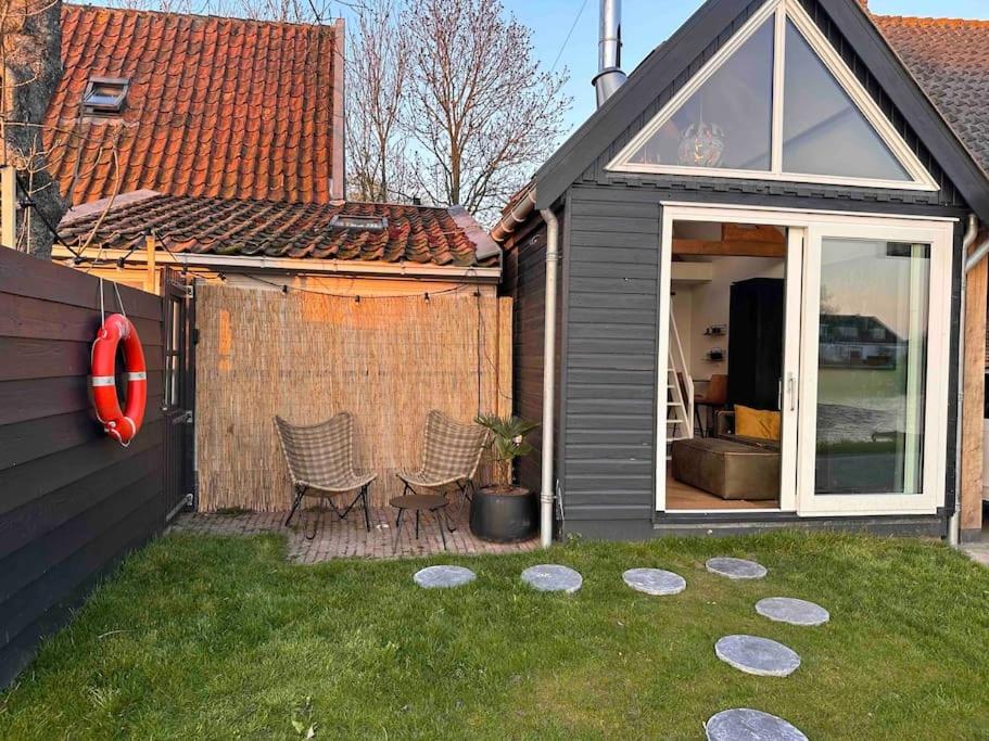 a backyard with two chairs and a house at Tiny house of Picasso in Warmenhuizen
