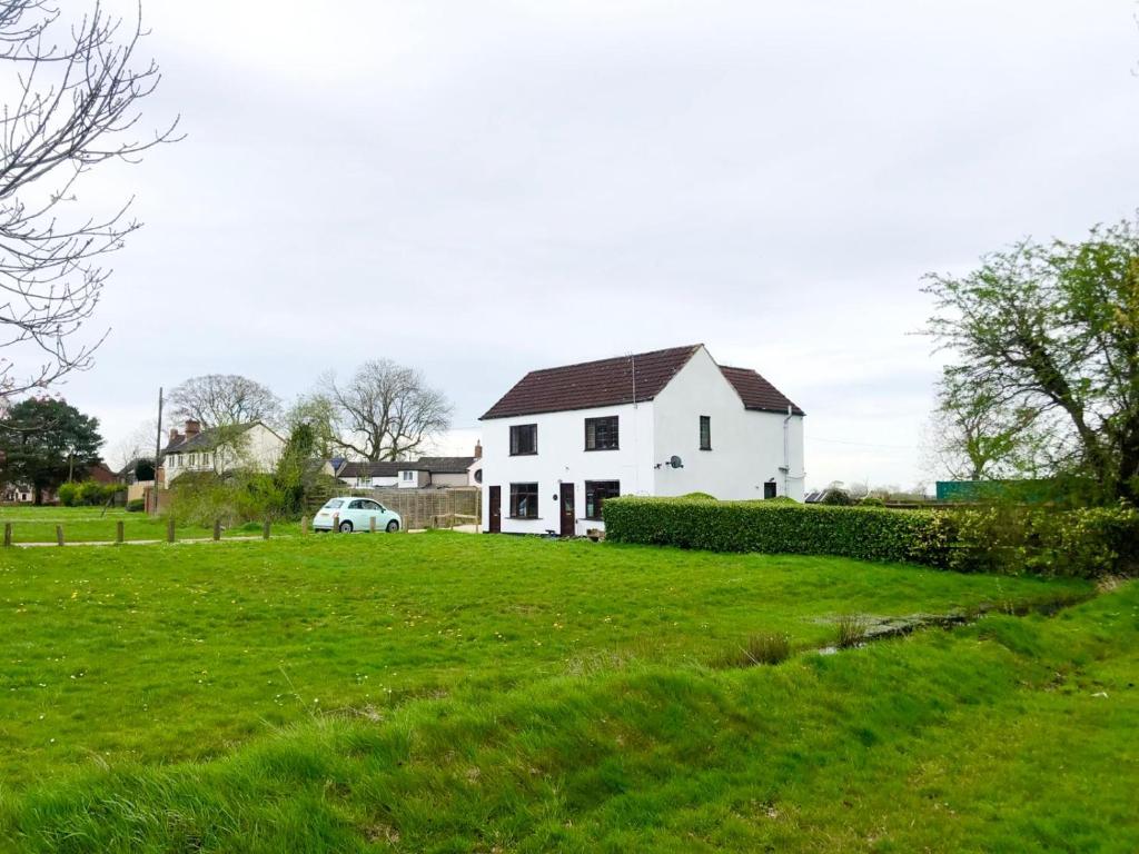 a white house in a field of green grass at Nice cottage in the countryside in Foleshill