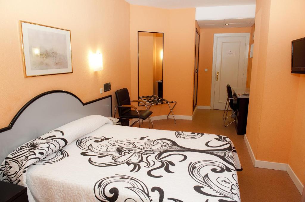 una camera con un letto con una coperta bianca e nera di Hotel Arha Santander a Santander