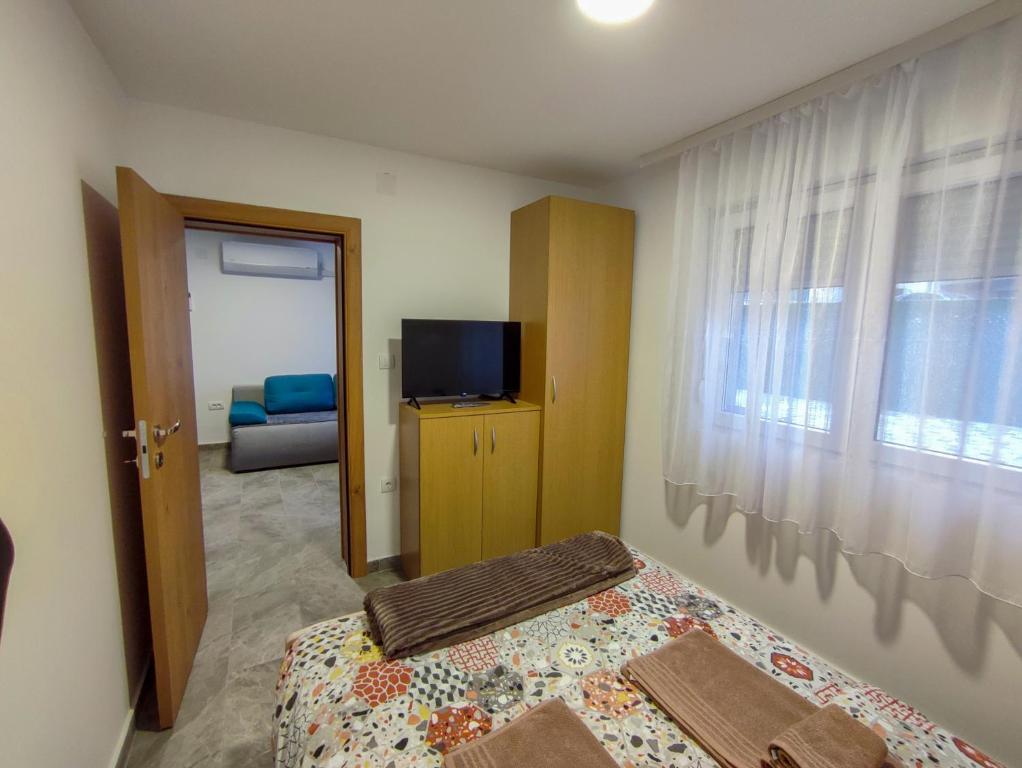 a bedroom with a bed and a tv and a window at MP Apartman in Soko Banja