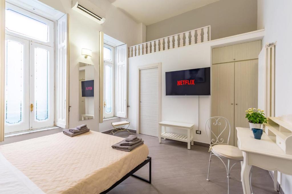 Un dormitorio con una cama, un escritorio y un televisor. en Napoli Relax Rooms Chiaia - Mergellina - Posillipo, en Nápoles
