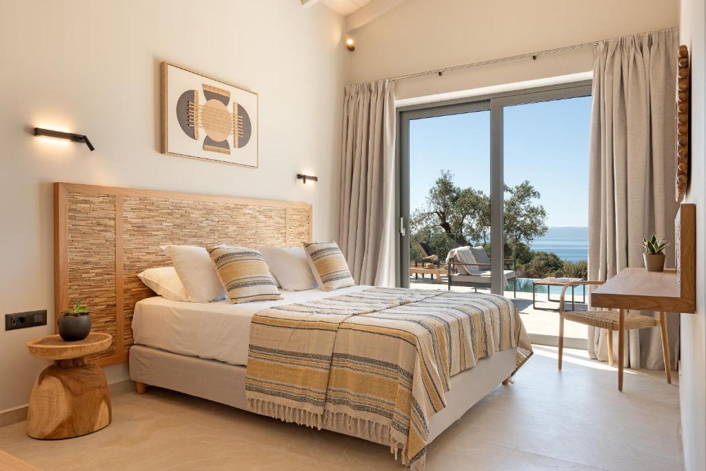 a bedroom with a bed and a large window at Luxury Stone Villas Kefalonia in Trapezaki