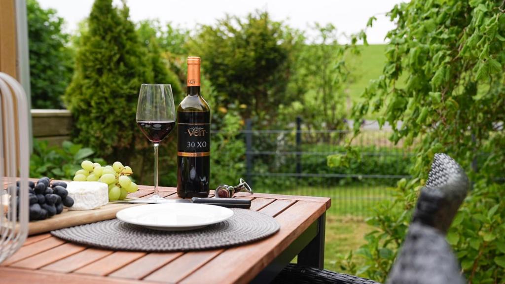 een fles wijn en een glas op een houten tafel bij gemütliches Ferienhaus hinterm Deich in Friedrichskoog