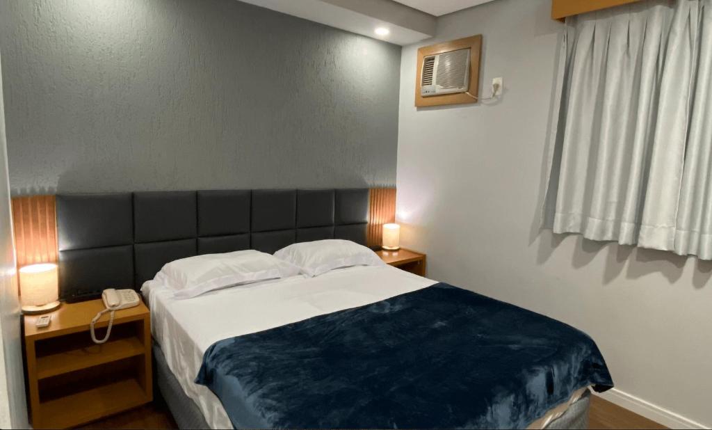 a bedroom with a large bed and a window at Flat confortável com recepção 24h e vaga de garagem in São Paulo