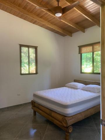 a bed in a room with two windows at Casa Tres Tucanes in Barú