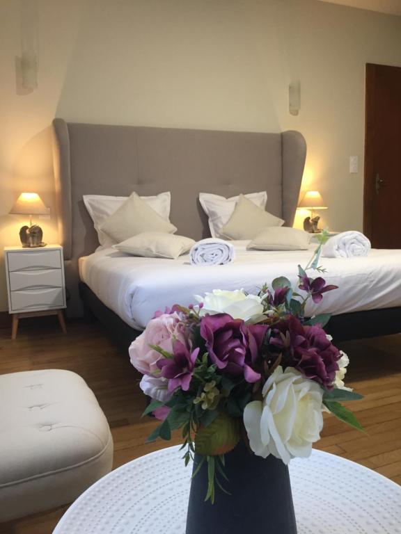 um quarto com uma cama com um vaso de flores sobre uma mesa em Domaine Bienvenue à la Saône em Montureux-lès-Baulay