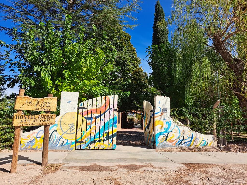 a gate with a sign and a fence with graffiti at Aire de Barreal Hostel Andino in Barreal