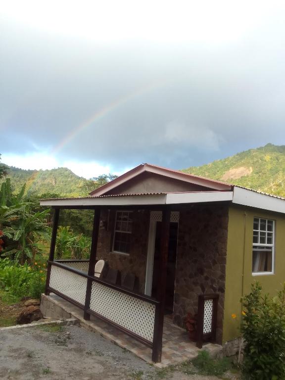 a small yellow house with a porch at River Splash Apartment & Cottage in Marigot
