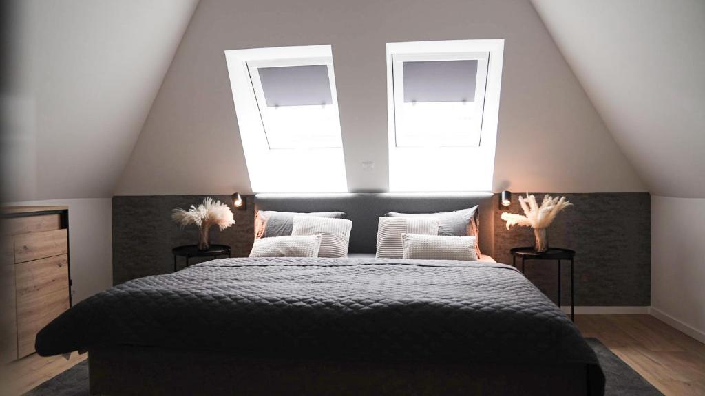 a bedroom with a large bed with two windows at Modernes Ferienhaus im Eidertal in Delve