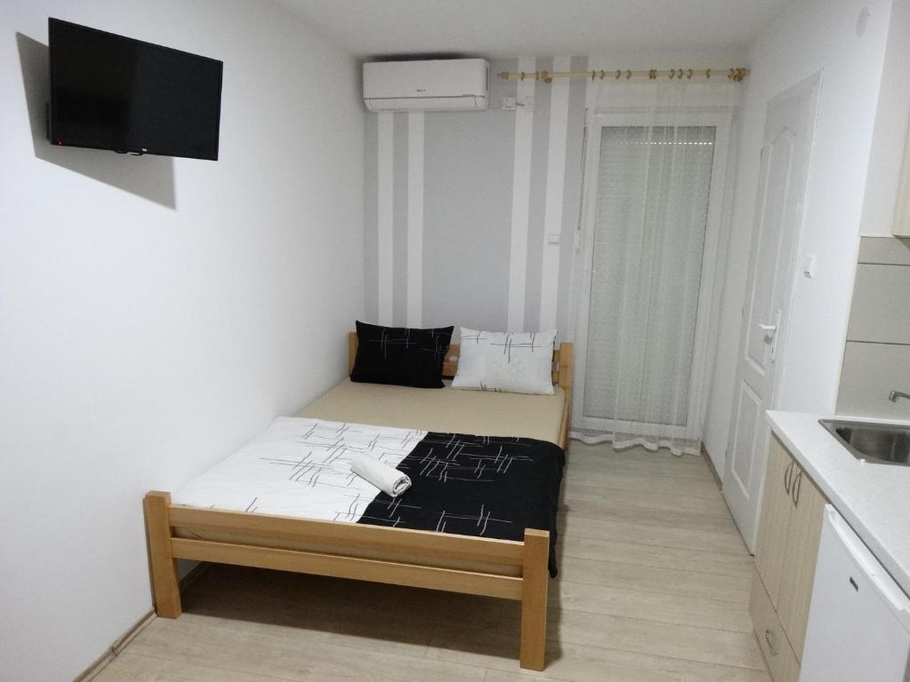 a small white room with a bed and a tv at Vila Jenic in Soko Banja