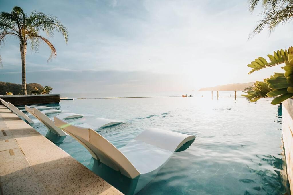 una piscina con sillas blancas en el agua en Villa Ocean Pearl Venao, en Playa Venao