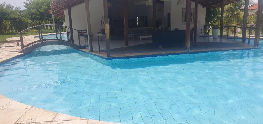 een groot blauw zwembad met een huis op de achtergrond bij House Anthony and Cleusa 36 Quinta do Rio in Pipa