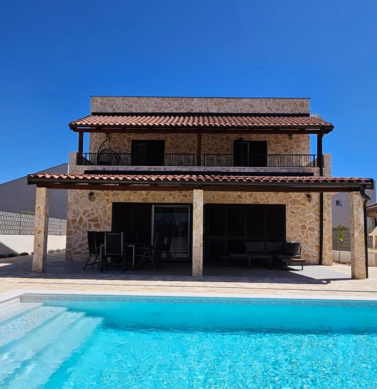 a house with a swimming pool in front of it at Vila Brod in Šibenik