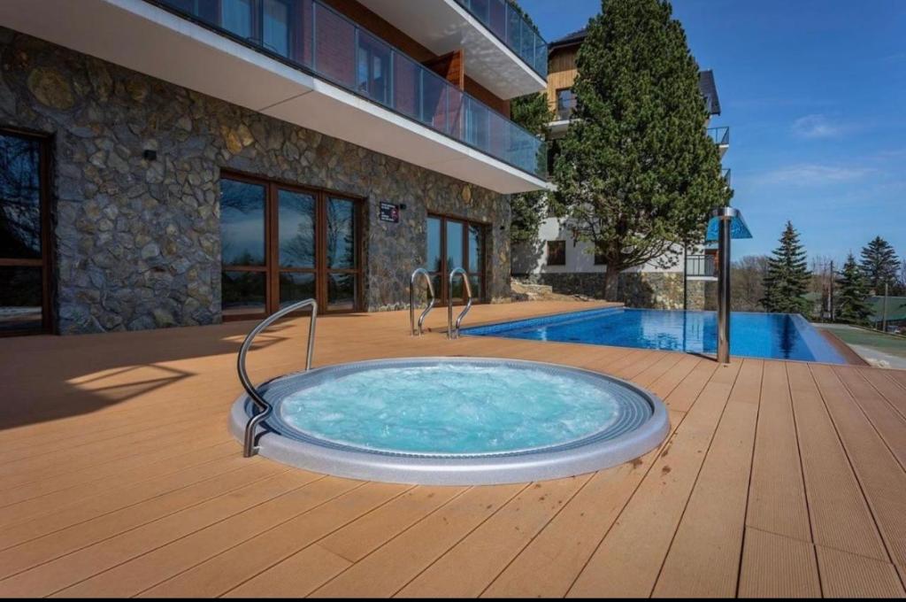 una bañera de hidromasaje en una terraza junto a una casa en Apartament Silence Green Park - Strefa SPA, en Szklarska Poręba