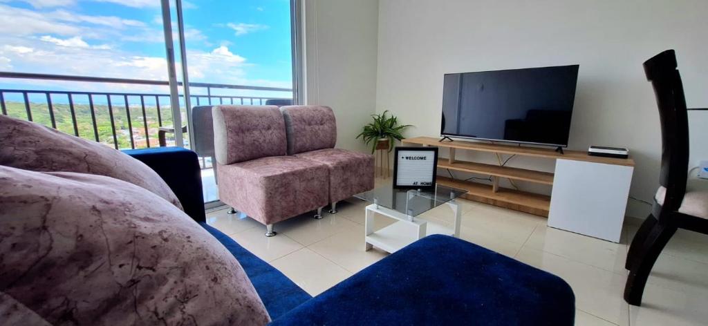 uma sala de estar com uma televisão, um sofá e uma cadeira em AG APTO con Aire Acondicionado em Neiva