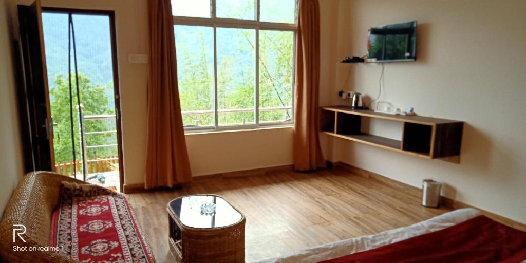 een woonkamer met een bank en een groot raam bij Majestic Zen Farmstay in Darjeeling