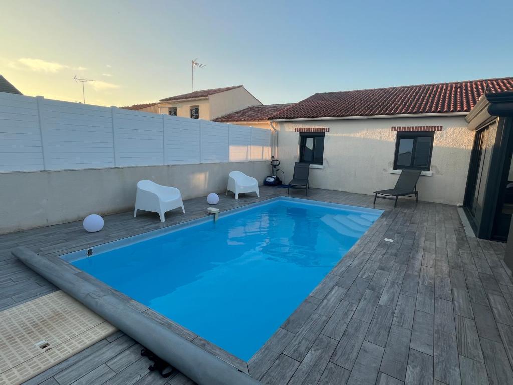 une piscine avec deux chaises et une maison dans l'établissement Villa avec piscine, à Saint-Jean-de-Monts
