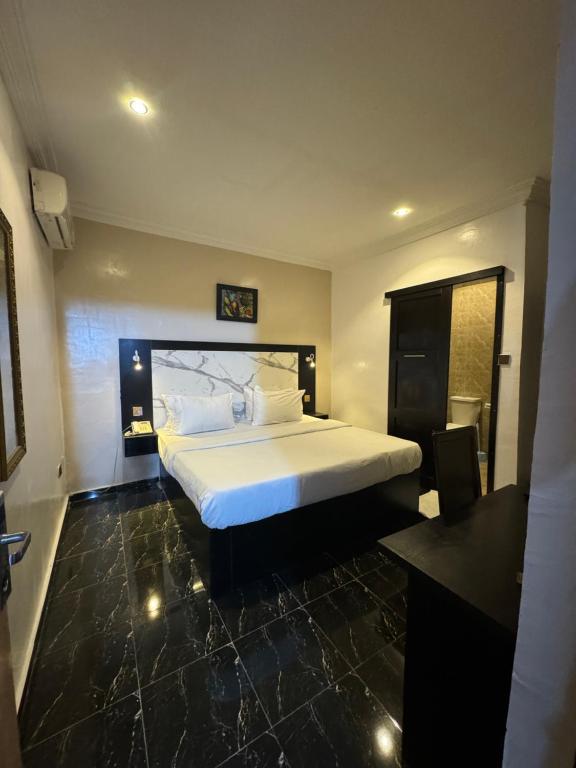 Posh Hotel and Suites Ikeja في إيكيجا: غرفة نوم مع سرير أبيض كبير في غرفة
