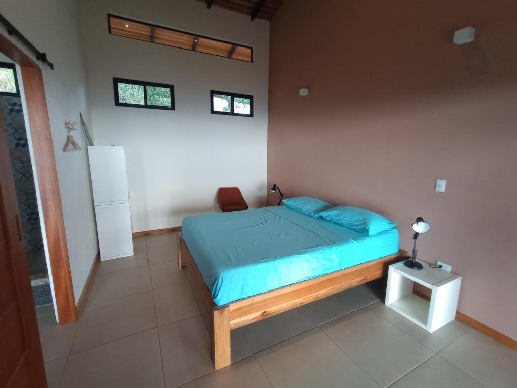 a bedroom with a bed with a blue comforter at VillaarcoirisCR in San Ramón