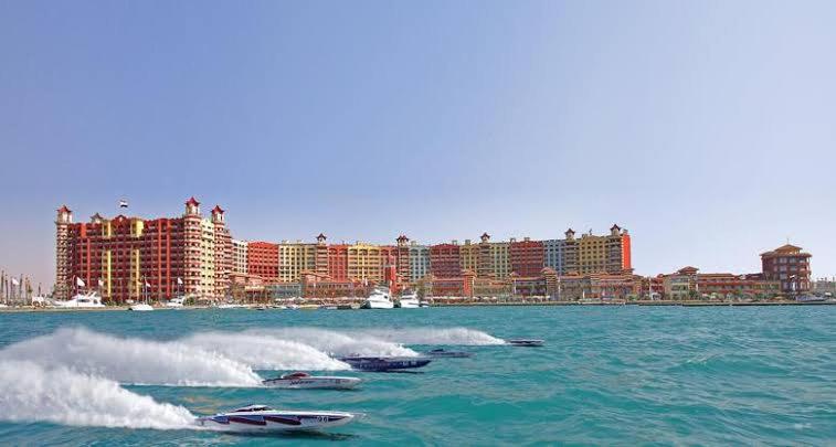 three boats in the water in front of a city at شاليه في بورتو مارينا الساحل الشمالي العلمين 59 in El Alamein