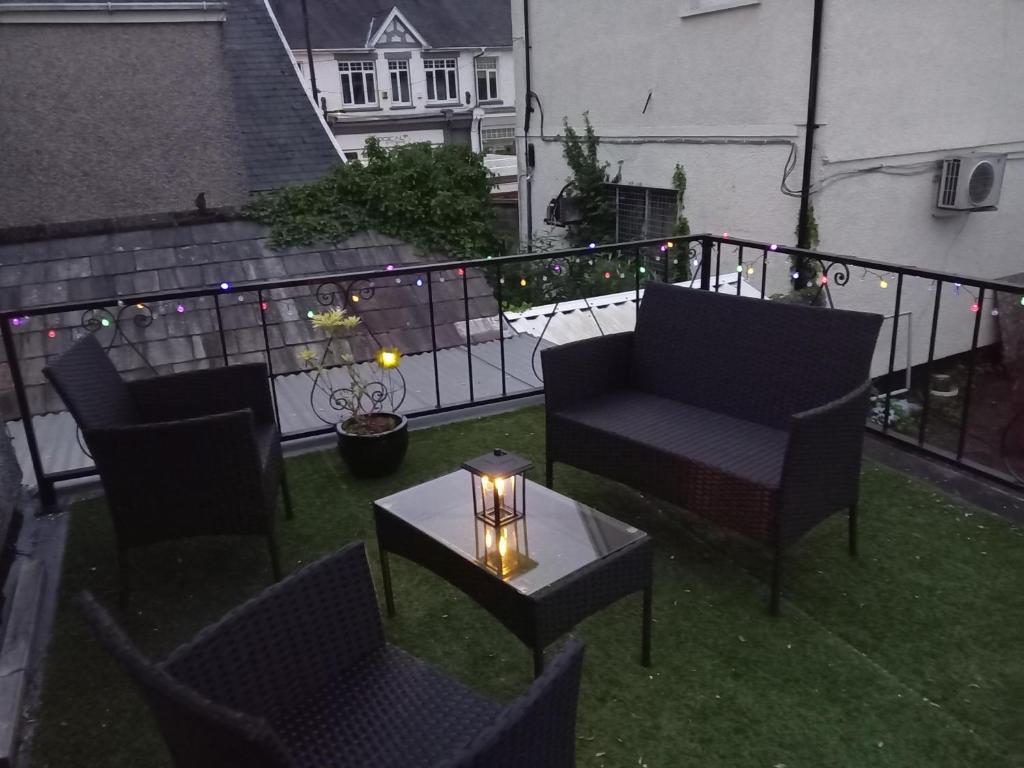 ein Balkon mit Stühlen und einem Tisch mit einer Kerze in der Unterkunft Cosy Central Hideaway near the Brecon Beacons in Ystradgynlais