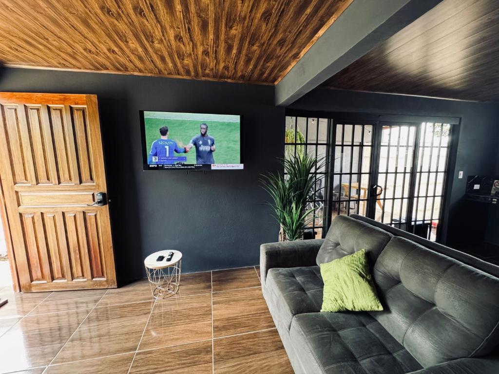 a living room with a couch and a flat screen tv at Jarkeyda House in Siquirres