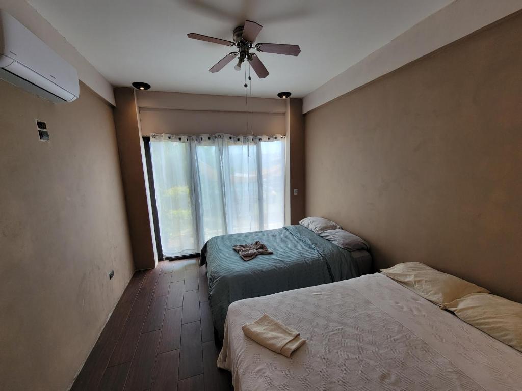 1 dormitorio con 2 camas y ventilador de techo en Restaurante y Hostal Romayor en El Congo