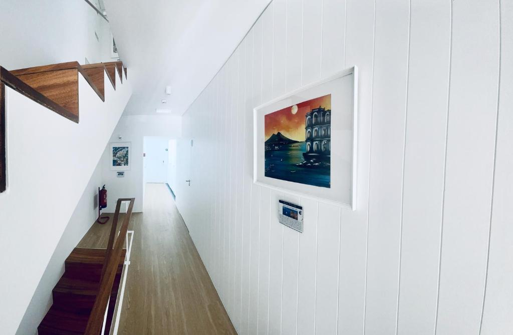 a hallway with a white wall with a painting on it at Partenope Hostel and Suites in Angra do Heroísmo